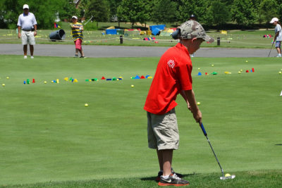 Child on golf course taking a swing with putter