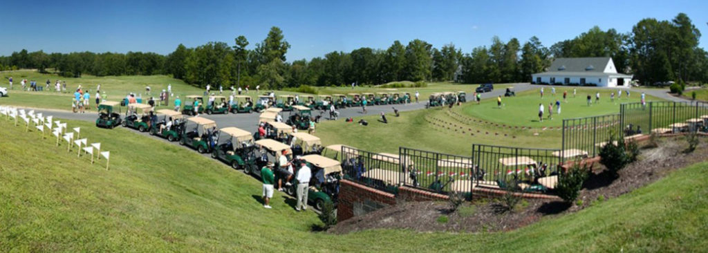 Panoramic view of golf course with row of golf carts