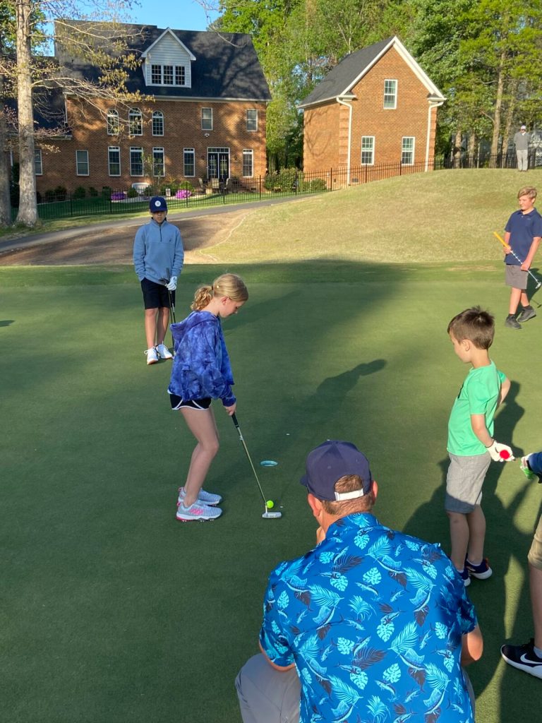 Reed Thorne instructing young golfers on golf course creen